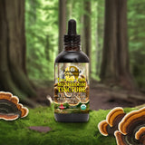 A bottle of Amanda Organics Turkey Jar Mushroom Tincture placed on green moss with large mushrooms around it, set against a blurred forest background.